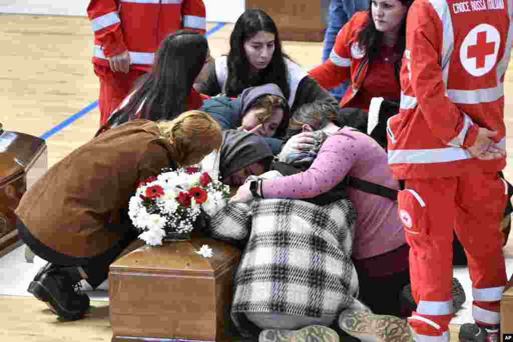 Relatives cry on the coffin of one of the victims of last Sunday's shipwreck, at the local sports hall in Crotone, Italy. At least 67 people died when their overcrowded wooden boat broke apart in rough water just off a beach in Calabria.