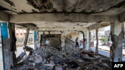 Boys walk past a destroyed classroom where people were sheltering at a school run by the U.N. Relief and Works Agency for Palestine Refugees that was previously hit by Israeli bombardment, in the Nuseirat camp in the Gaza Strip on June 7, 2024.