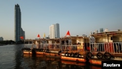FILE - The Bangkok skyline is seen behind tourist boats on the Chao Phraya river in downtown Bangkok, Thailand, Feb. 4, 2021.