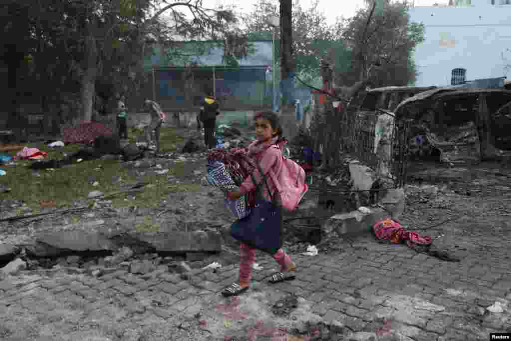 A girl carrying her belongings walks in the area of Al-Ahli hospital where hundreds of Palestinians were killed in a blast that Israeli and Palestinian officials blamed on each other, and where Palestinians who fled their homes were sheltering, in Gaza City. REUTERS/Mohammed Al-Masri 