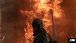 This handout photograph taken on June 12, 2024, and released on June 13, 2024, by the Ukrainian Emergency Service shows a firefighter trying to stop a fire at an industrial facility damaged following an air strike, in the Kyiv region.