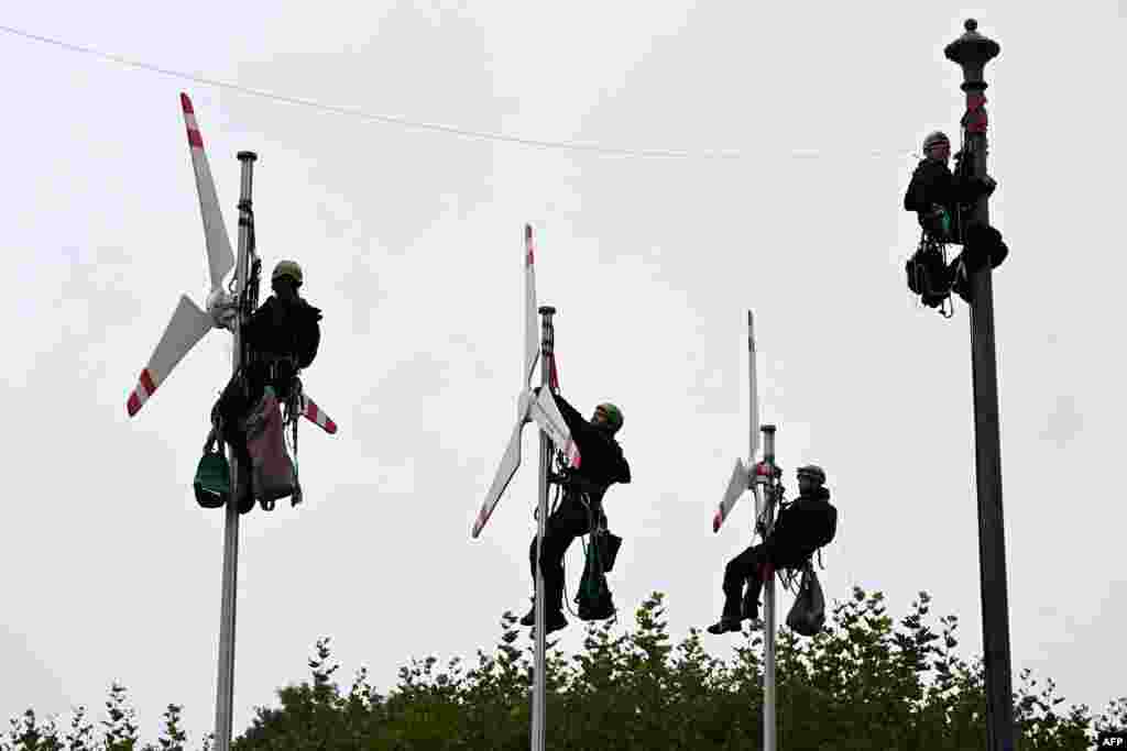 Greenpeace activists climb up flagpoles to fix mockups of wind turbines in front of the Bavarian State Chancellery in Munich, Germany, as they call for more wind power.