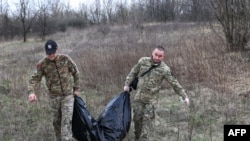Members of a Ukrainian Civil-Military Cooperation team carry the remains of a Russian soldier in the village of Synykha, in Ukraine's Kharkiv region, April 8, 2023.