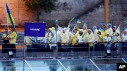 Ukraine's athletes wave Ukrainian flags aboard a boat as it makes its way along the Seine river in Paris, France, during the opening ceremony for the 2024 Summer Olympics, July 26, 2024. 