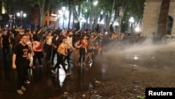 Law enforcement officers use a water cannon to disperse the crowd near the parliament building during a rally to protest against a bill on "foreign agents" in Tbilisi, Georgia, April 30, 2024.