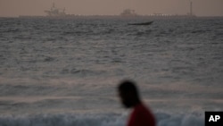 A man walks on the beach past an offshore gas terminal in Saint Louis, Senegal, Jan. 19, 2023.