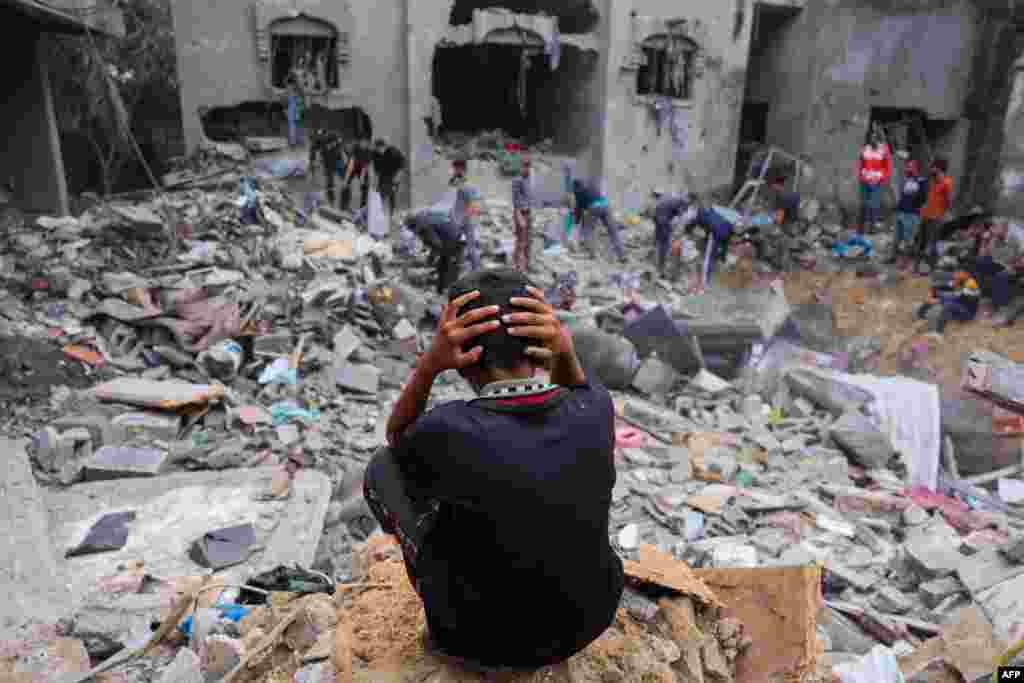 Mtoto ashanga akiwatizama watu wanavuta vitu chini ya vifusi baada ya jengo kubomolewa na shambulio la Israel huko Rafah kusini mwa Ukanda wa Gaza, Nov. 12, 2023.