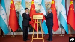 Nan foto sa a ke ajans nouvel Xinhua pataje ak lapres Minis Afe Etranje Chinwa a Qin Gang (a goch) ak Minis Afe Etranje Onduras la Enrique Reina devwale plak anbasad Onduras la nan Peken, 11 Jyen 2023. 