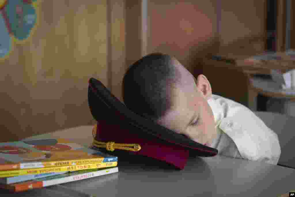 A young cadet takes a nap at the first lesson in a cadet lyceum on the first day at school in Kyiv, Ukraine. Children and students went to school despite the fact that Kyiv was hit by massive Russian missile barrage early in the morning, causing fires, damaged buildings and infrastructure objects. 