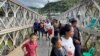 Pengungsi Myanmar melintasi jembatan yang menghubungkan Myanmar dan India, 15 November 2023. China mengatakan pihaknya membantu memukimkan kembali orang-orang yang melintasi perbatasannya untuk menghindari bentrokan di Myanmar utara. (Foto: Ilustrasi/Reuters)