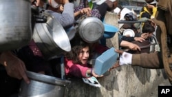 FILE - Palestinians line up for free food during the ongoing Israeli air and ground offensive on the Gaza Strip in Rafah, Jan. 9, 2024.