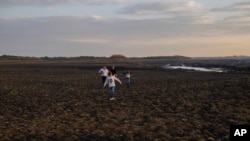 Una familia camina sobre el seco río Santa Lucía en el embalse Paso Severino en Florida, Uruguay, el martes 4 de julio de 2023.