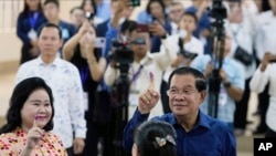 2023 年7 月23 日，柬埔寨首相洪森（右）與妻子文·拉尼（左）在柬埔寨金邊東南部塔克穆阿的一個投票站投票後，展示了沾有墨水的手指。