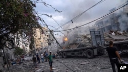 Palestinyen mache pami debri yon katye ke atak ayeryen Izrael yo detwi nan Gaza Siti, 10 Oktob, 2023.