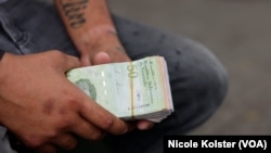 ARCHIVO - Hombre sostiene varios billetes de bolívares en Caracas, Venezuela, el 10 de abril de 2023.