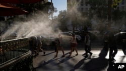 FILE - Pedestrians walk under cooling misters on a hot day in Las Vegas, Nevada, July 13, 2023. A recent study shows that intense and perpetual heat in the United States, Mexico and Central America is the result of human-caused climate change.  