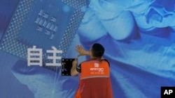 一名工人在上海举办的世界人工智能大会上检查中国科技公司中科曙光展示的芯片和自主字样的屏幕。（2023年7月5日）