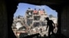 Seorang remaja berdiri depan lubang yang tadinya sebuah dinding pada sebuah bangunan yang dihantam roket Israel, di Khan Yunis, di selatan Jalur Gaza, 8 November 2023. (Foto: Mahmud Hams/ AFP)