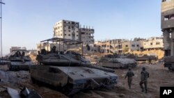 Twoup Izrayelyen bo kote yon bilding ki detwi pandan yon operasyon lame a nan Gaza, 8 Novanm, 2023.