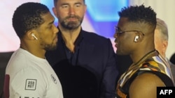 Anthony Joshua et Francis Ngannou se regardent après une conférence de presse précédant leur combat de boxe, Riyad, le 6 mars 2024.