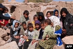 Anak-anak Afghanistan duduk di dekat rumah mereka yang rusak akibat gempa bumi di desa Wardakha, distrik Zendeh Jan, Provinsi Herat pada 10 Oktober 2023. (Foto: AFP)