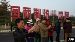 中國福建廈門豎立起一個台灣金門島可以看到的「一國兩制統一中國」的大型標語牌，遊客在前拍照。 （2024年1月12日）
