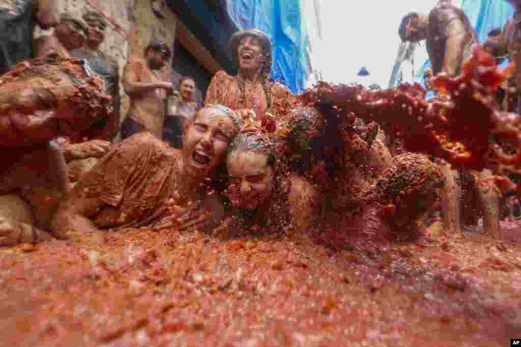 Revelers lie in a pool of squashed tomatoes during the annual "Tomatina" tomato fight fiesta, in the village of Bunol near Valencia, Spain.