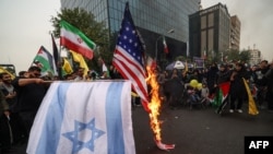 Para pedemo membakar bendera Israel dan AS dalam unjuk rasa di luar gedung bekas Kedutaan Besar AS di Teheran, iran, Sabtu, 4 November 2023. (Foto: Atta Kenare/AFP)
