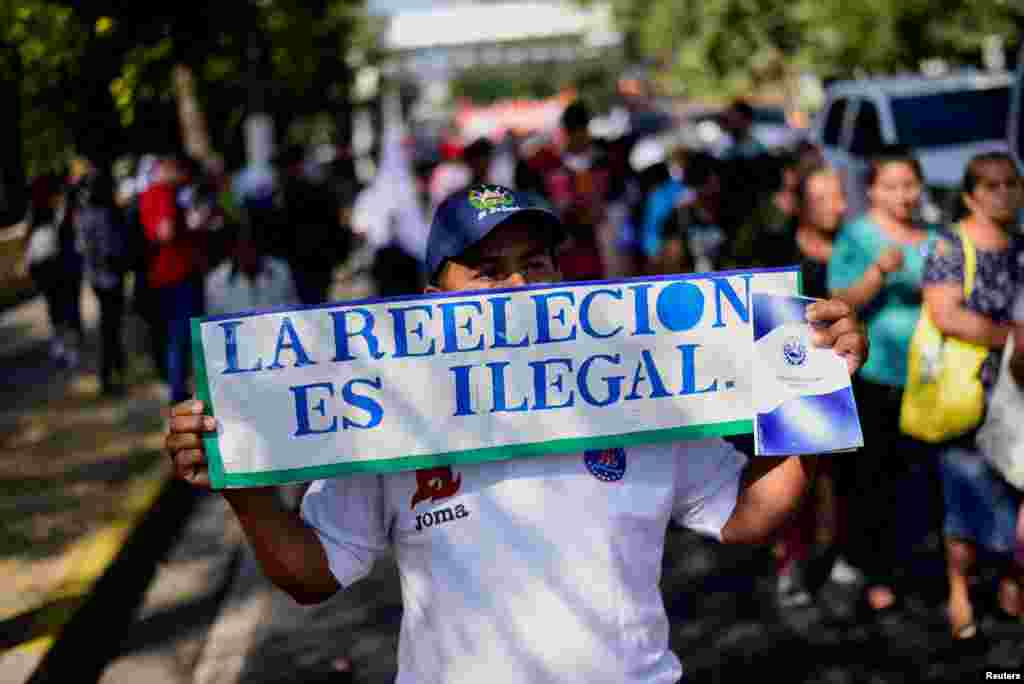 Un hombre sostiene un cartel que dice "La reelección es ilegal" durante la protesta para conmemorar el 32º aniversario de la firma de los acuerdos de paz en El Salvador.