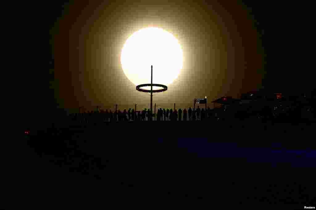 A supermoon, known as the Blue Moon, the first supermoon of the year, rises next to the Marina Bay Sands hotel in Singapore.