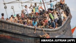 Pengungsi Rohingya yang baru tiba terdampar di perahu karena masyarakat sekitar memutuskan untuk tidak mengizinkan mereka mendarat setelah memberikan air dan makanan di Pineung, Aceh, 16 November 2023. (Foto: AMANDA JUFRIAN/AFP)