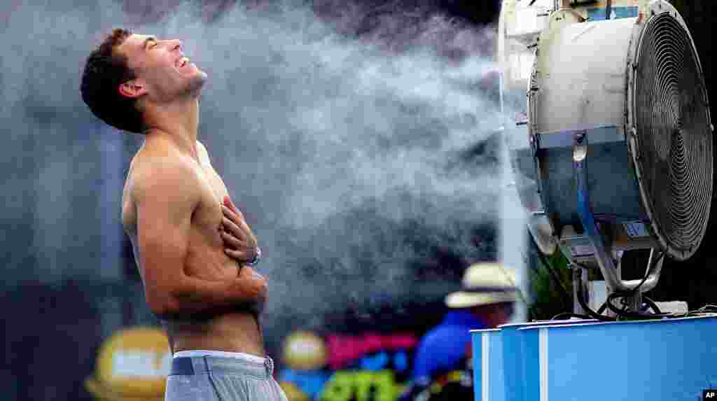 Poland's Jerry Janowicz is sprayed with cool water at the Australian Open tennis championship in Melbourne. The Australian Open organizers implemented the Extreme Heat Policy when the temperature topped 43°C (109°F) and play was halted for just over fours on the outside courts but continued on the covered show courts.