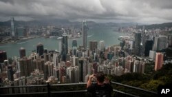 FILE - A visitor sets up his camera in the Victoria Peak area to photograph Hong Kong's skyline, Sept. 1, 2019.