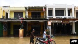People push a motorbike in a flooded street following the passage of typhoon Noru in Hoi An city, Quang Nam province on Sept. 28, 2022.