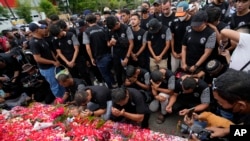 Players and officials of the soccer club Arema FC pray outside the Kanjuruhan Stadium where many fans lost their lives in a stampede Saturday night in Malang, Indonesia, Oct. 3, 2022.