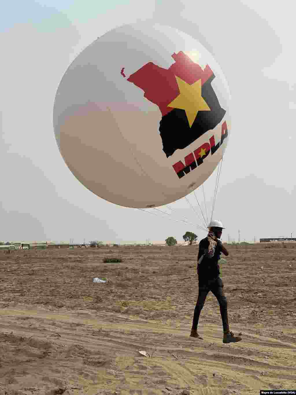 Um jovem carrega um balão com o mapa de Angola e o símbolo e cores do partido MPLA. Camama, Luanda.