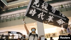 Seorang aktivis pro demokrasi melambaikan bendera dalam unjuk rasa di mal New Town Plaza di Hong Kong, 12 Juni 2020. 
