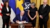 Predsednik SAD Džo Bajden potpisuje Protokol o pristupanju Švedske i Finske NATO-u, u društvu potpredsednice Kamale Haris, švedske ambasadorke Karin Olofsdoter i finskog ambasadora Mika Hautale, 9. avgust 2002. 