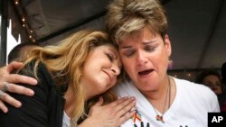 Pulse nightclub owner Barbara Poma comforts Orlando City commissioner Patty Sheehan, right, June 12, 2017, during a ceremony at the club in Orlando, Florida, on the one-year anniversary of the June 12, 2016, shooting that killed 49.