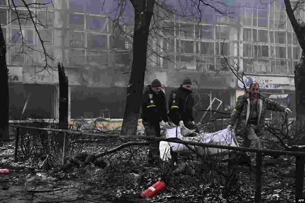 Police officers move the bodies of passersby killed in yesterday's airstrike that hit Kyiv's main television tower in Kyiv, Ukraine.