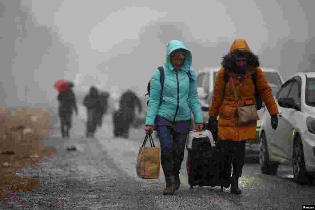 People fleeing Russia's military operation against Ukraine walk toward the Shehyni border crossing to Poland past cars waiting in line to cross the border, outside Mostyska, Ukraine.