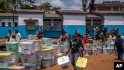 Mfanyakazi wa tume ya uchaguzi akibeba masunduku ya kura kwenye kituo cha kukusanya na kujumlisha kura mjini Nairobi, Agosti 10, 2022. Picha ya AP