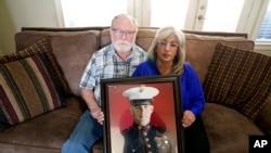 Joey dan Paula Reed berpose sambil membawa foto anak mereka yang ditahan di Rusia, Trevor, di rumah mereka di Fort Worth, Texas, pada 15 Februari 2022. (Foto: AP/LM Otero)