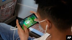 Seorang anak memainkan game "Honor of Kings" yang populer dari platform game China "Tencent" dalam kereta berkecepatan tinggi dari Henan ke Beijing, 15 September 2021. China menetapkan aturan baru yang membatasi waktu yang dapat dihabiskan anak-anak untuk bermain game online.(AP)