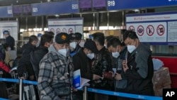 Pelancong mengenakan masker antre di konter check-in penerbangan internasional di Bandara Internasional Ibu kota Beijing, China, 29 Desember 2022.