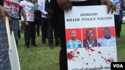 FILE - A protester holds a sign picturing human rights attorney Willie Kimani, his client Josephat Mwenda and their taxi driver Joseph Muiruri allegedly killed by police, at a rally in Nairobi, Kenya, July 4, 2016. (J. Craig/VOA)