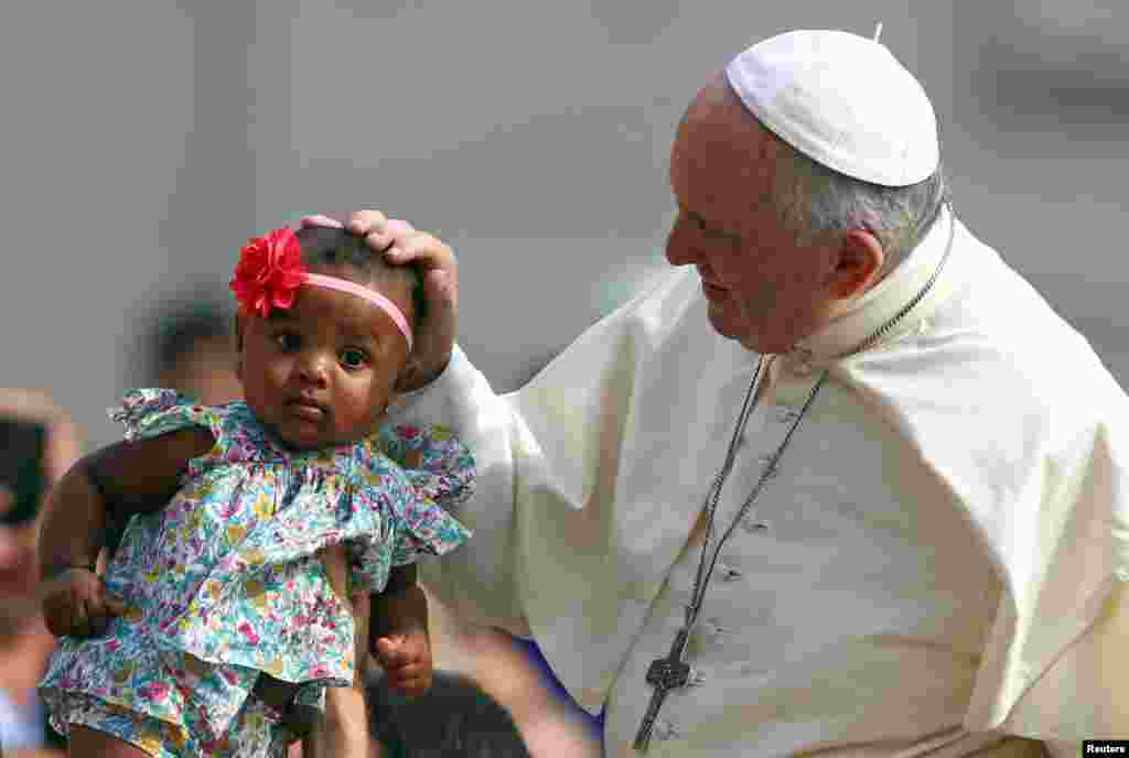 Pope Francis blesses a child as he arrives to lead the Wednesday general audience in Saint Peter's square at the Vatican.