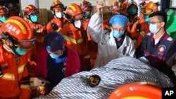 In this photo released by Xinhua News Agency, rescuers transfer a ninth person pulled from the rubble 88 hours after a self-built residential building collapsed in Changsha, central China's Hunan Province, May 3, 2022.