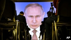 FILE - Journalists watch as Russian President Vladimir Putin gives his annual state of the nation address in Manezh in Moscow, Russia, March 1, 2018. 