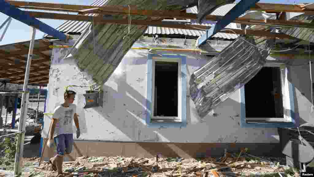 A man walks past a house damaged by recent shelling on the outskirts of the southern coastal town of Mariupol, Ukraine, Sept. 7, 2014.
